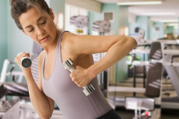 B7H5M6 Hispanic woman using hand weights in health club